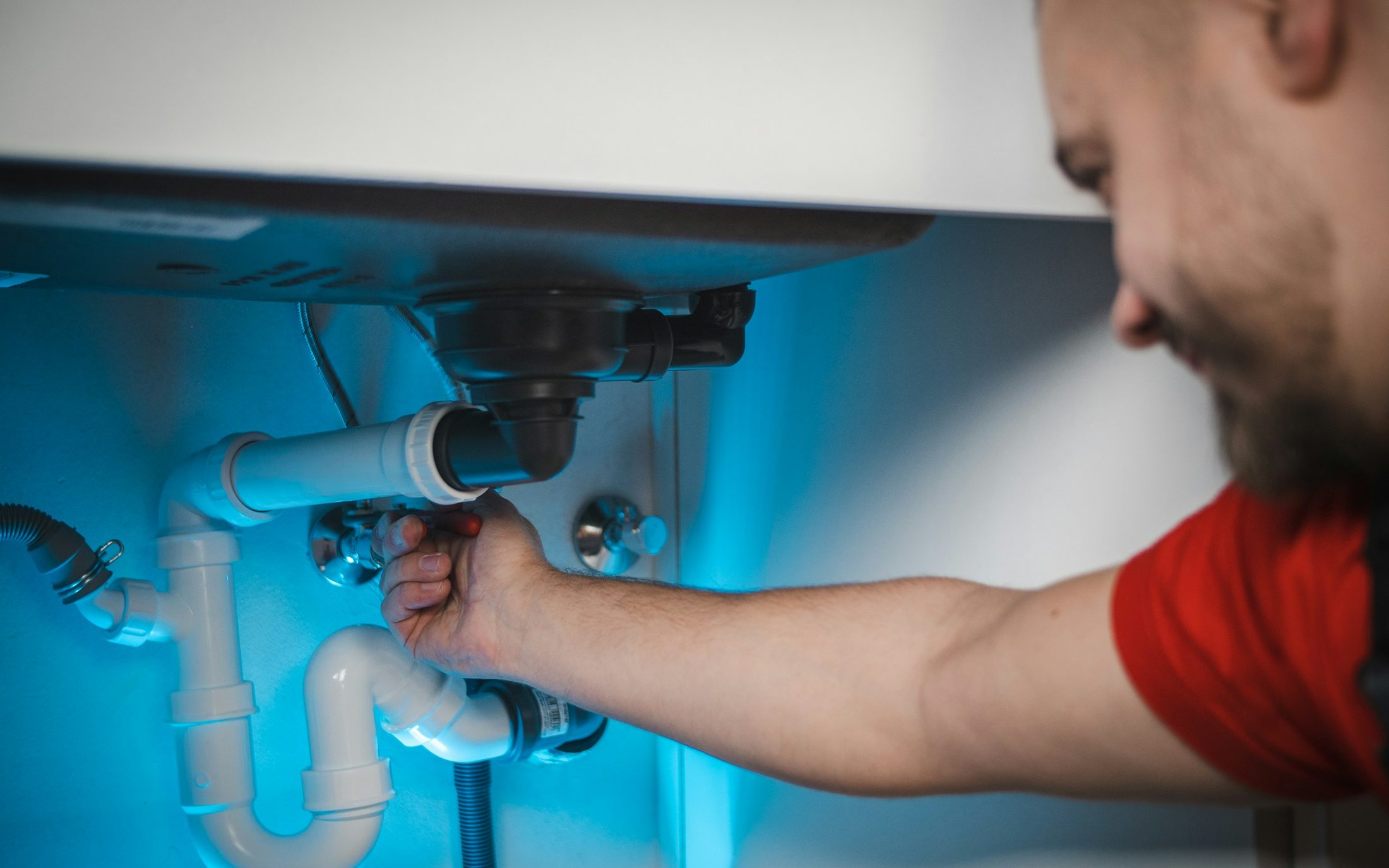 Plumber's hand tightening a fitting under a sink mid-repair